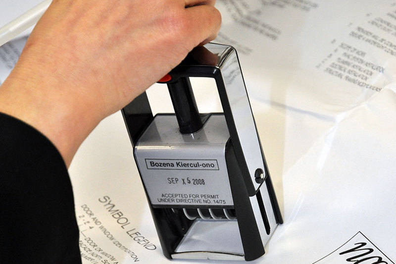 Hand of employee holding a stamp, applying it to official documents