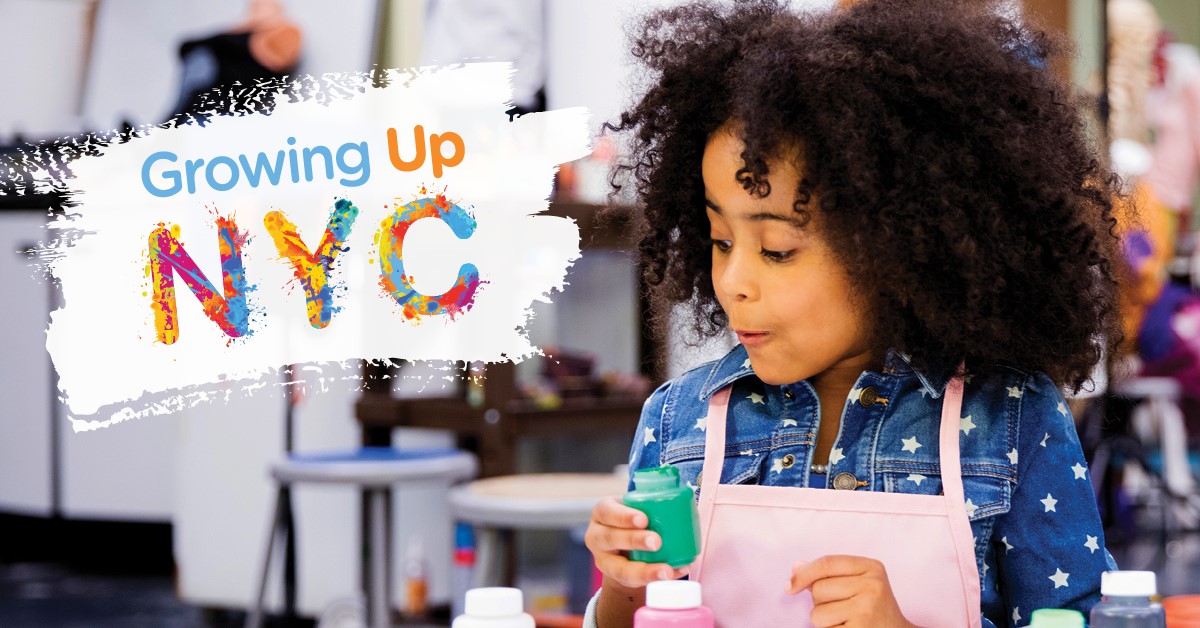 little girl with pink apron, holding a green jar of paint in hand and looking down