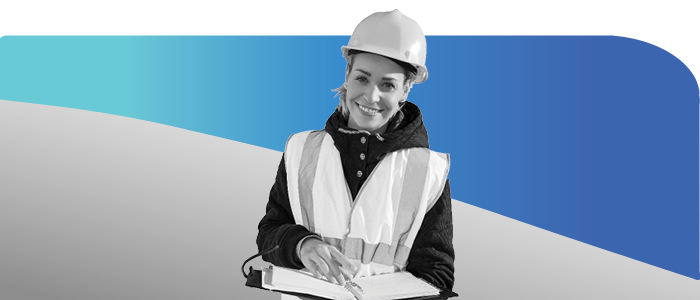 Smiling female skilled trades worker with safety vest, hardhat, and clipboard