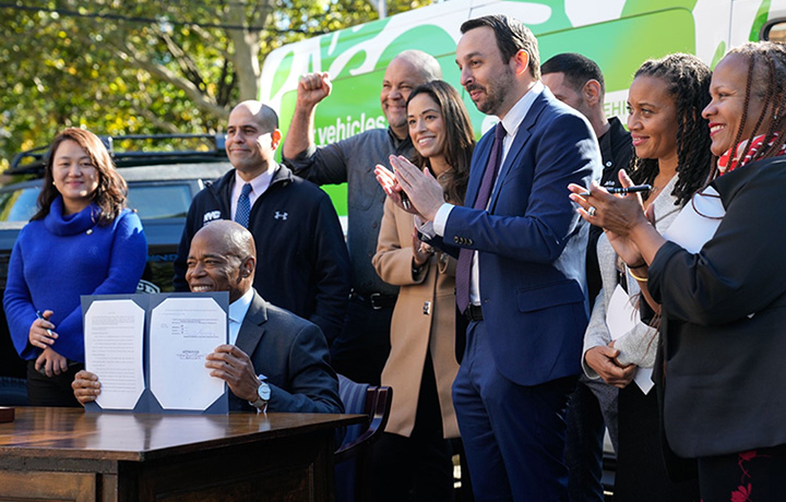 Mayor Adams holds the all-electric fleet local law that he signed.
                                           