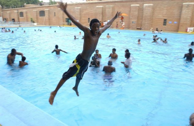 A boy jumps into a pool.