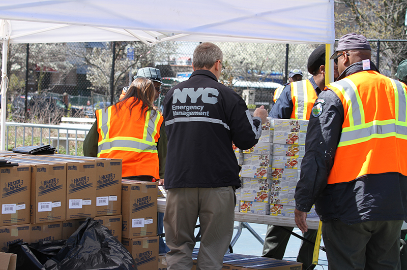 A NYC Emergency Management staff member distributing boxes with volunteers.
                                           