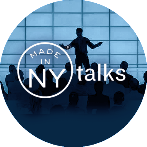Silhouette of a person standing on stage talking to people. Made in NY Talks.