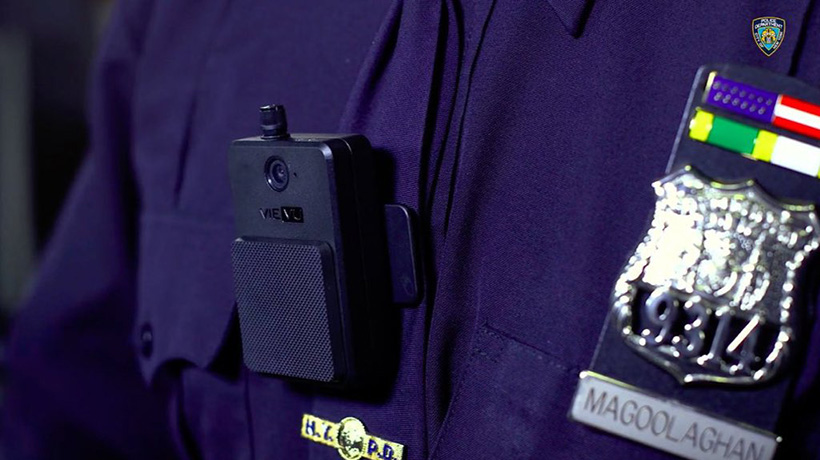 Close up of a body-worn camera clipped to the uniform shirt of a police officer