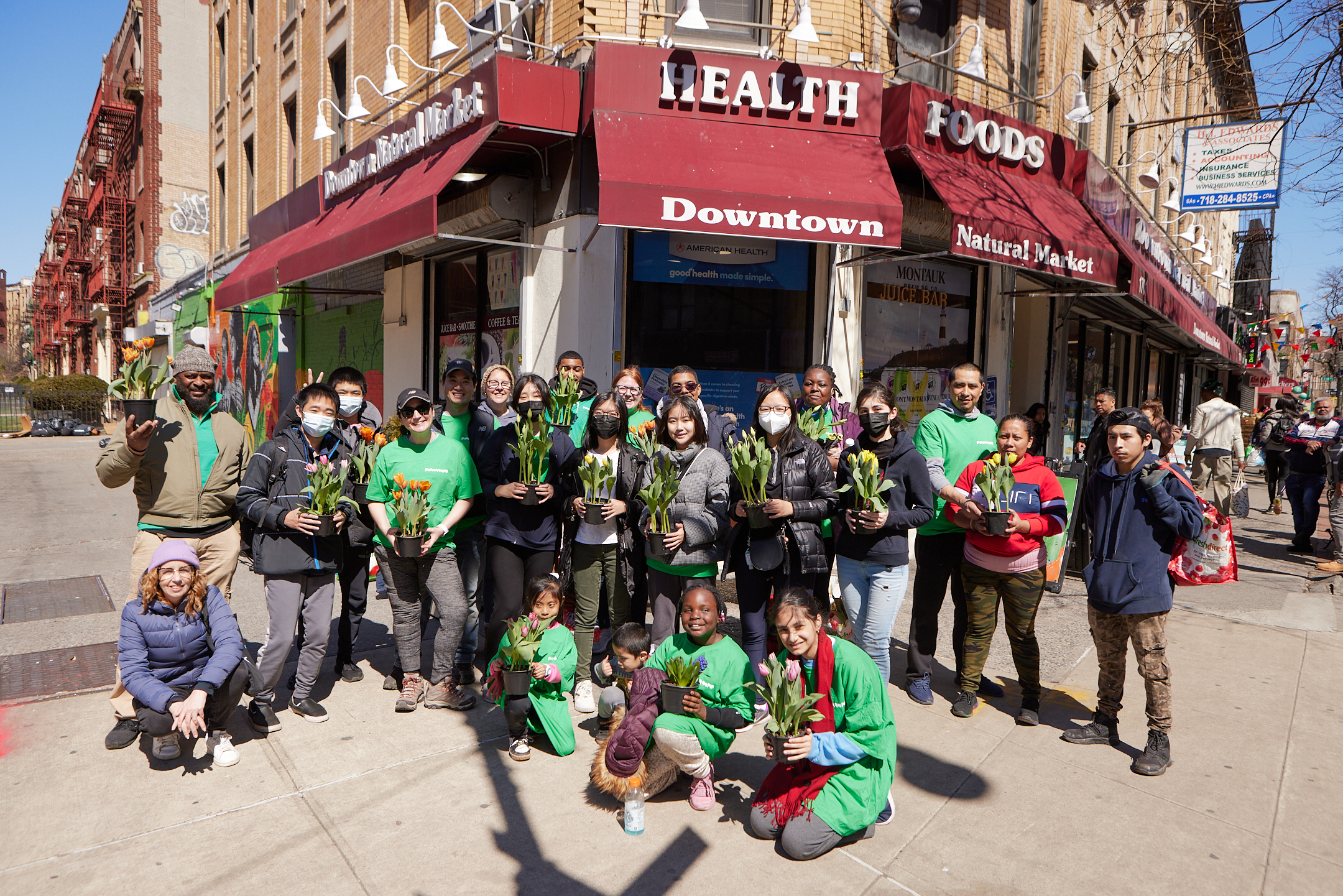 Group of people holding flowers in front of a business in Church Flatbush BID
                                           