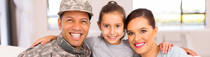Smiling veteran in uniform with his wife and child