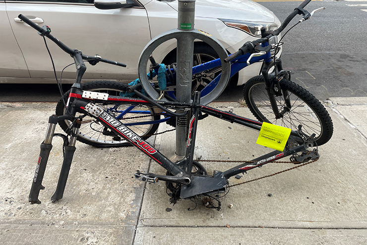Two derelict or unusable bikes attached to a bike rack.