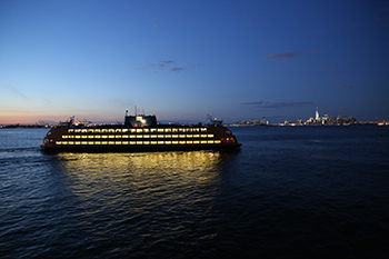 At night a ferry travels in the New York harbor.