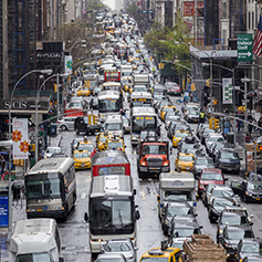 Cars, buses, trucks, and taxis on a congested street in Midtown Manhattan.