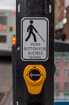 An accessible pedestrian signal affixed to a pedestrian signal pole.