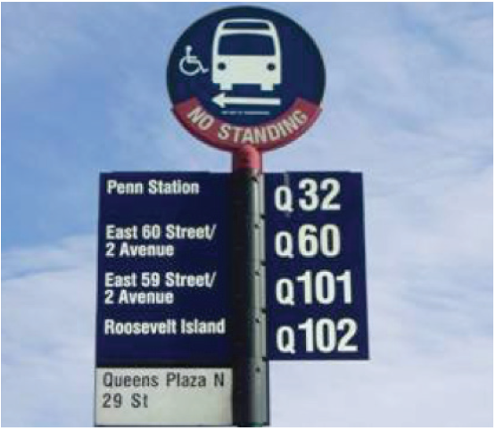 A round blue sign position on the top of a pole with a bus and accesibility icon with the words No Standing. Lower on the pole are bus route numbers and bus station names