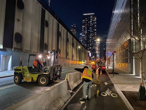 NYC DOT crews install Jersey barriers along a protected bike lane in Manhattan.