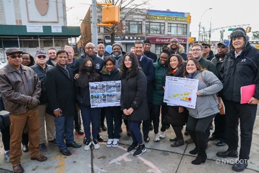 A group of people stand together outside in Queens near an intersection that was recently redesigned.