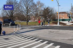 A group of pedestrians cross a street, walking over new crosswalk under a traffic signal, while vehicular traffic is stopped.