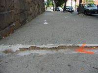 A sidewalk has an uneven surfacing creating a trip hazard.
